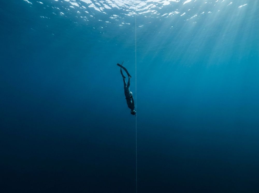 Apneísta descendiendo en agua azul profunda